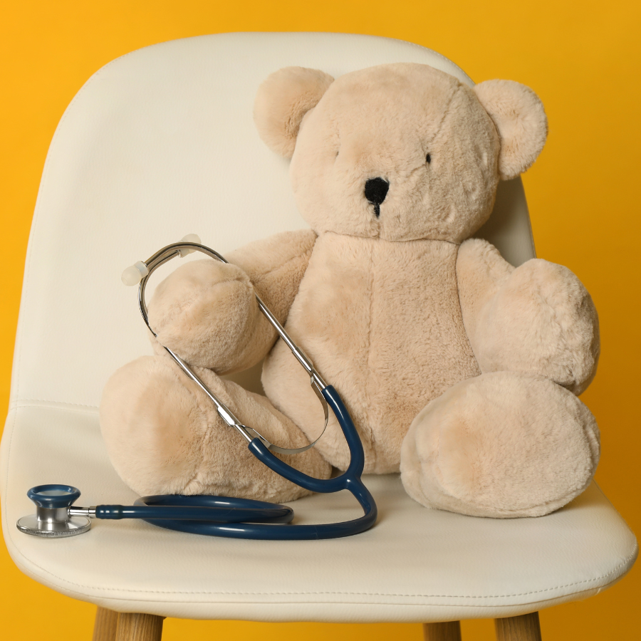 Teddy bear sitting on chair with yellow background
